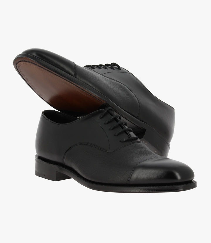 This photo presents one Loake Fullerton shoe resting atop the other, creating a layered visual effect. The contrast between the polished upper and the leather sole is apparent, and the image captures the shoe's overall craftsmanship. The toe cap and detailed stitching are clearly visible, emphasizing the attention to detail that defines this premium footwear.