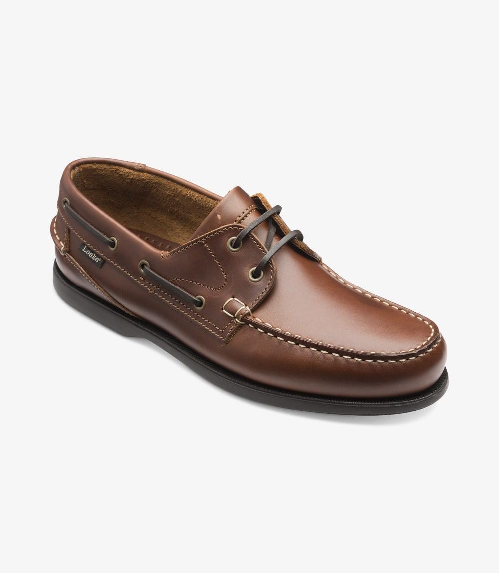 An angled view of the Loake 524-DIS Brown Boat Shoe, capturing the elegance of the leather upper, moccasin construction, and the robust rubber deck sole. The lacing system and eyelets are clearly visible, adding to the shoe's stylish yet functional design, perfect for a relaxed, summer look.