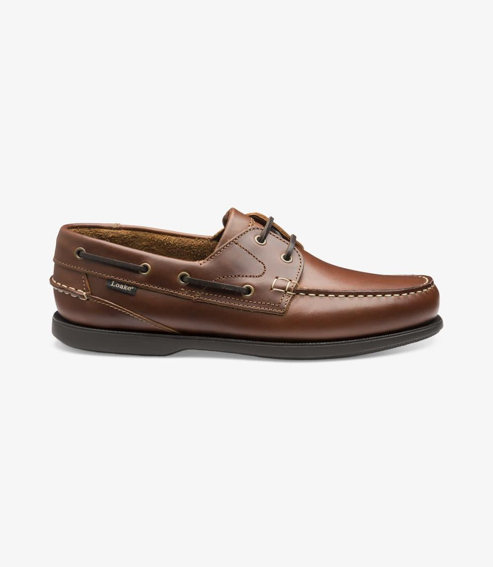 A side view of the Loake 524-DIS Brown Boat Shoe, showcasing its smooth brown leather upper and classic boat shoe design. The moccasin rubber deck sole is visible, highlighting the shoe's durability and flexibility. The fine stitching detail along the side enhances the shoe's refined, yet casual aesthetic.