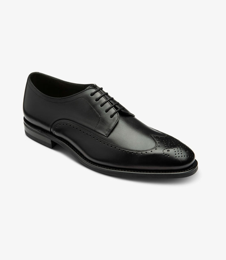 This angled shot captures the Loake Bale Black Derby Brogue from a dynamic perspective, accentuating the intricate punched brogue design on the toe and along the eyestay. The curvature of the shoe is evident, providing a glimpse of the well-crafted leather lining and the sturdy rubber sole that promises comfort and support.