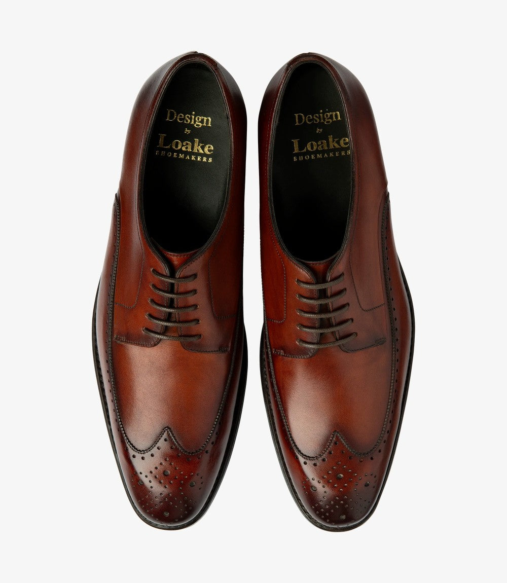 From above, both Loake Bale Scotch Derby Brogues are presented side by side, emphasizing their symmetrical design. The fine leather finish glistens softly under the light, while the contrast between the brogue perforations and the smooth leather creates visual interest. The Goodyear welt construction is visible, showcasing the quality craftsmanship inherent in these men's shoes.