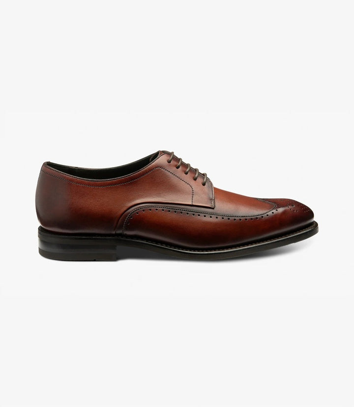 The Loake Bale Scotch Derby Brogue showcases its elegant profile in a side view, featuring a polished calf leather upper in a rich scotch hue. The distinct brogue detailing along the eyelet panel and toe cap highlights the craftsmanship, while the Goodyear welted shadow rubber sole offers a sturdy yet stylish foundation.