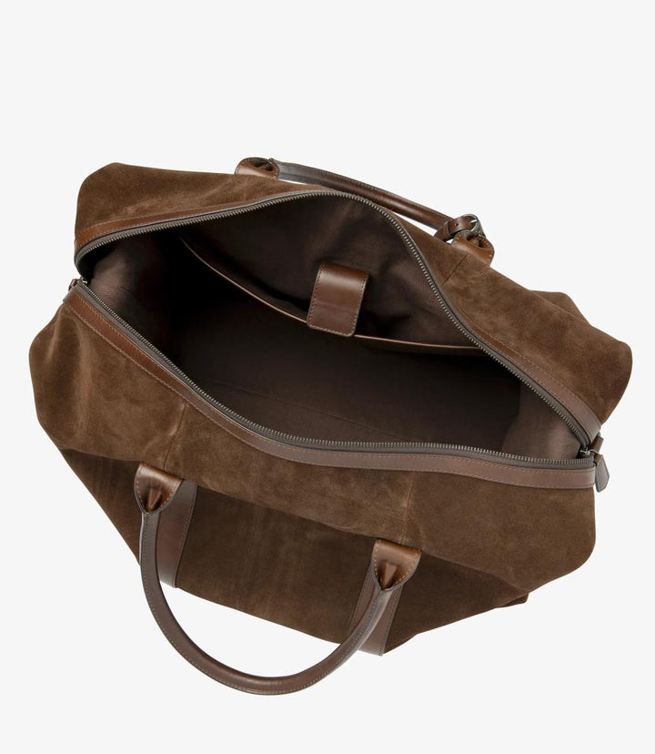 The interior view of the Loake Balmoral Polo Suede Weekend Bag reveals its thoughtfully designed layout. The spacious main compartment is lined with a soft, durable material that protects your belongings. The full-width internal Velcro-fastened pocket dominates one side, ensuring easy access to essentials, while the single internal zip pocket is visible, perfect for organizing smaller items. This interior shot showcases the bag's practicality, combining style with functional storage options.