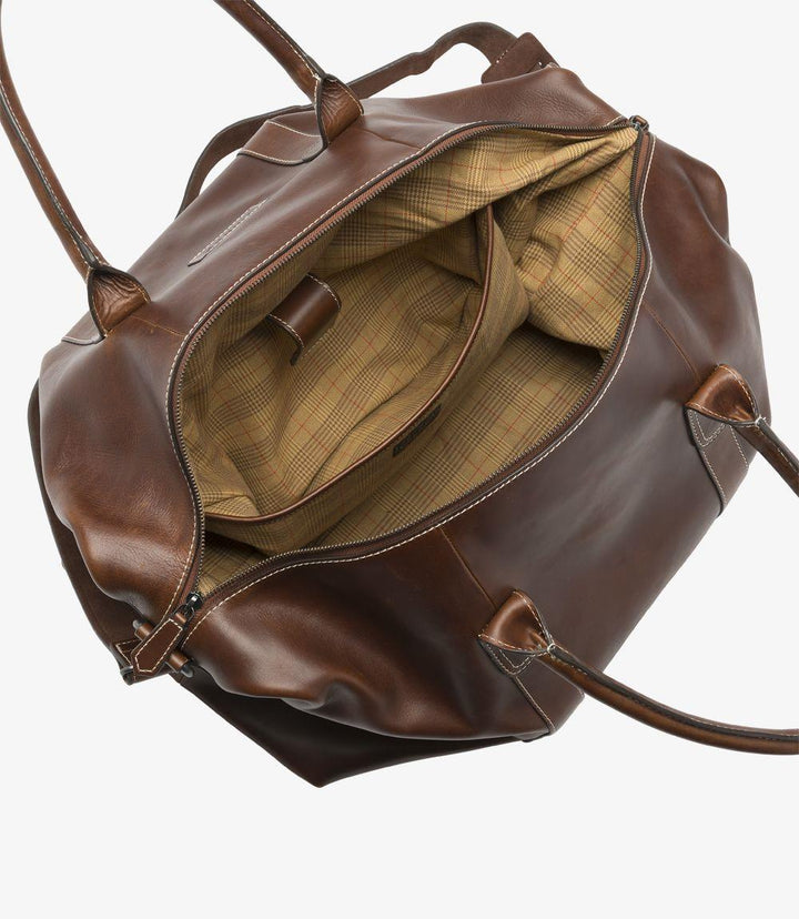 The interior of the Balmoral weekend bag reveals its practical and well-organized design. A full-width Velcro-fastened pocket runs along one side, providing ample space for essential items. The single internal zip pocket offers additional security for smaller belongings. The lining material complements the bag’s leather exterior, ensuring a sophisticated and functional interior.