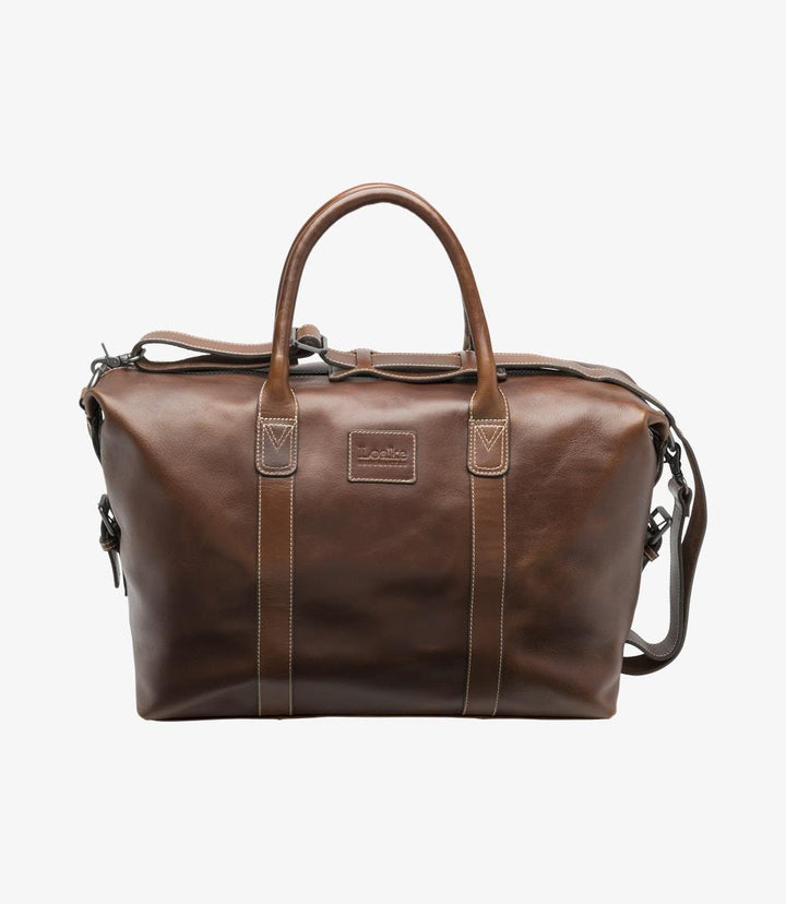 The exterior of the Loake Balmoral Brown Leather Weekend Bag showcases its refined brown vegetable-tanned leather, which exudes elegance and durability. The sleek, classic design is highlighted by the sturdy leather handles and detachable shoulder strap. The polished finish and robust construction reflect the bag’s premium quality, making it ideal for stylish travel.