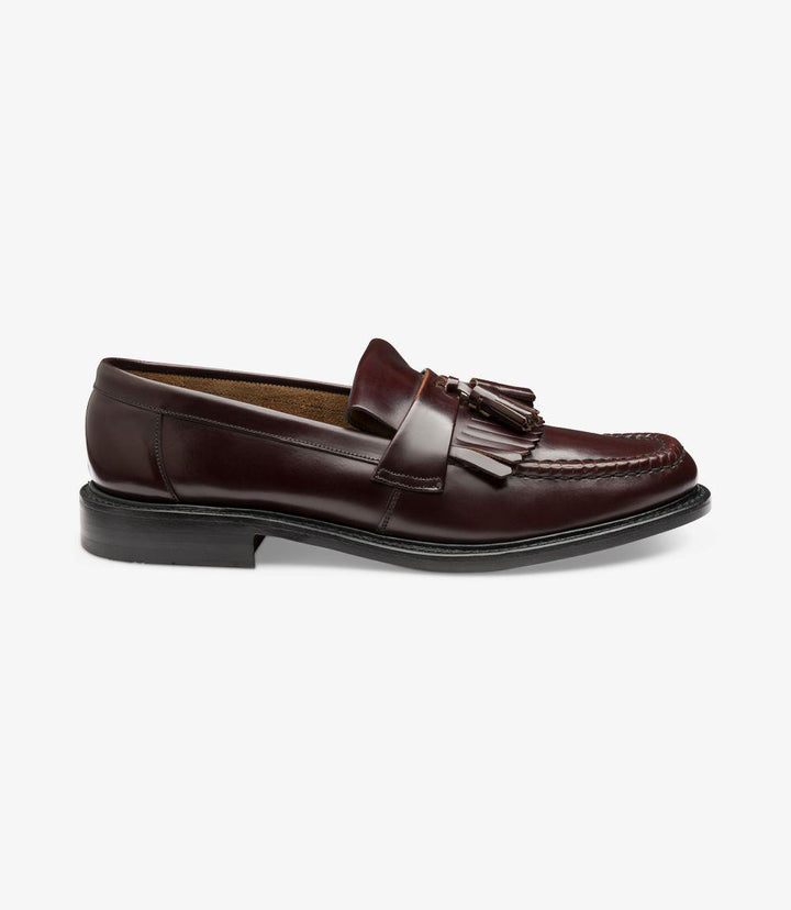 A detailed image of the Brighton-DIS Burgundy Loafer Slip-On from the side, showcasing the polished leather finish and elegant tassel design. The Goodyear welted leather sole is prominently displayed, emphasizing the shoe's quality and craftsmanship.