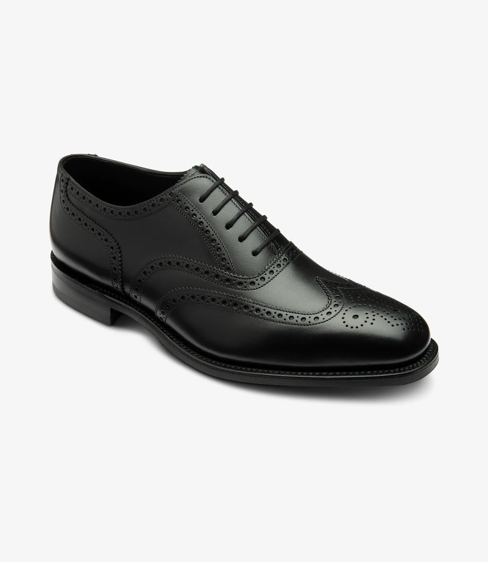 This angled view captures the Loake Buckingham Oxford Brogue from a dynamic perspective, emphasizing its sleek lines and the slightly chiseled toe shape. The intricate broguing patterns and rich leather texture are prominently displayed, while the rubber sole offers a practical yet stylish contrast, making this shoe suitable for both formal and everyday wear.