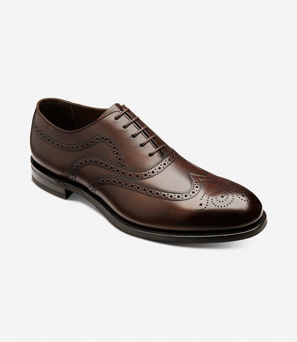 This angle showcases the Loake Castlegate Oxford Brogue from a slight diagonal, emphasizing the refined curvature of the 'minster' last shape. The image reveals the luxurious calf leather in all its glory, with a close-up on the brogue perforations and the distinctive Goodyear welted shadow rubber soles. The leather lining and insole are hinted at, hinting at the exceptional comfort inside.