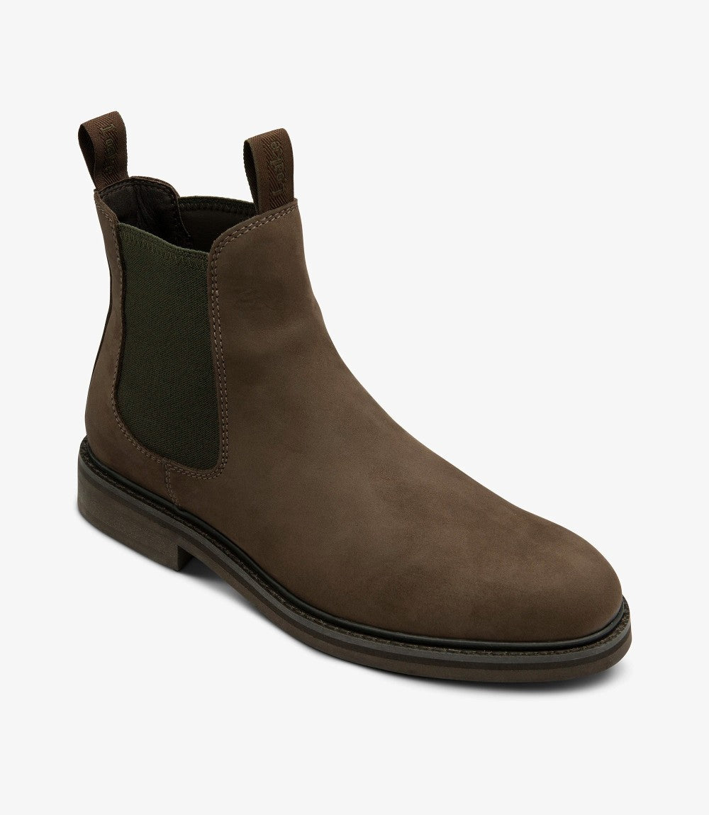 This photo presents the Loake Ducksworth Chelsea Boot from a dynamic angle, highlighting both the front and side. The distinctive curves of the boot are accentuated, showcasing the smooth texture of the oiled nubuck. The subtle stitching details along the seams add an element of craftsmanship, while the rounded toe maintains a classic Chelsea boot shape.