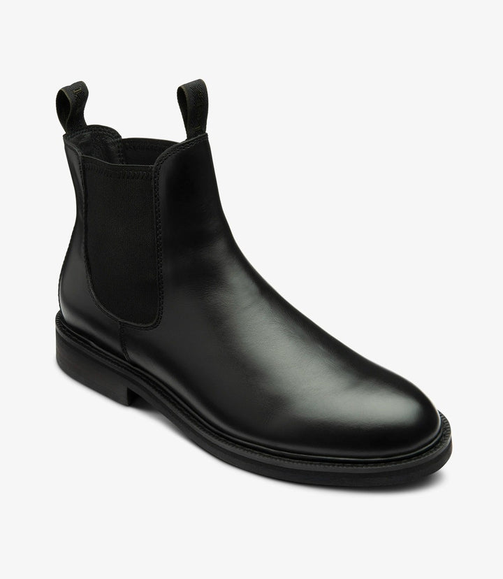 Captured from an angle, this image highlights the elegant curvature of the Loake Ducksworth Chelsea Boot. The profile accentuates the boot’s waxy leather finish, which appears rich and supple. The elastic side panel is slightly stretched, demonstrating its flexibility and ease of access. The slight lift from the rubber sole is evident, promising comfort without sacrificing style, making these boots a perfect choice for both formal and casual settings.