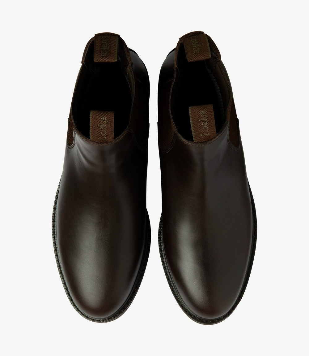 This overhead shot captures both Ducksworth Chelsea Boots side by side. The symmetry of the design is evident, and the clean lines of the boots are complemented by the contrasting texture of the waxy leather. The elastic panels are prominent, indicating the ease of slipping the boots on and off, while the comfortable footbed and quality craftsmanship are implied through the overall presentation.