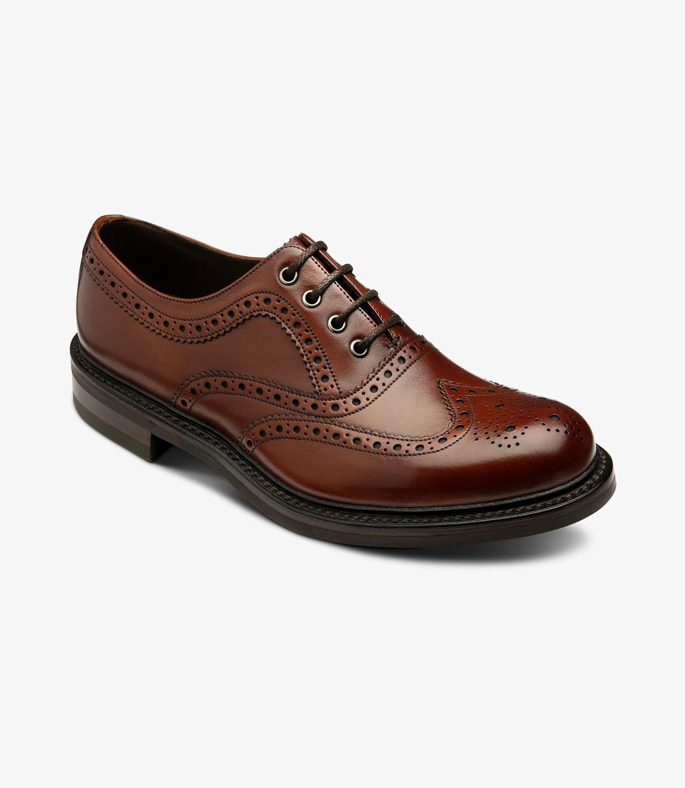 This angle reveals the striking wingtip design of the Edward brogue, emphasizing the precise perforations and elegant curves. The shoe's polished mahogany finish catches the light beautifully, accentuating the craftsmanship. The slightly elevated profile showcases the rubber sole's construction, promising both comfort and style.