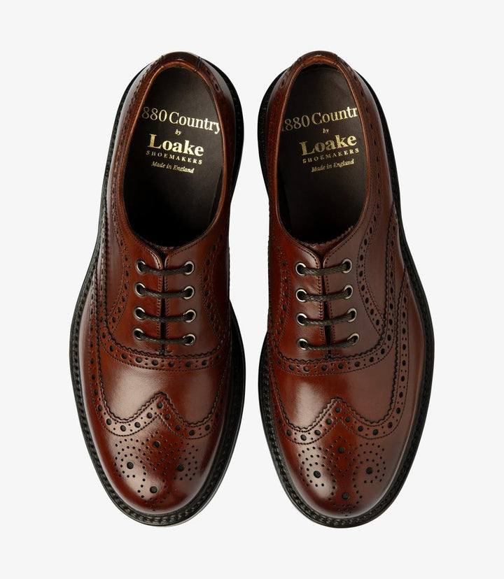 The overhead shot displays both Loake Edward Mahogany Oxford Brogues side by side, highlighting their symmetrical design. The hand-painted leather shines with a warm, deep hue, while the brogue detailing is prominent. The rubber soles are visible, reflecting a blend of modernity and tradition, perfect for a range of occasions from formal to casual.