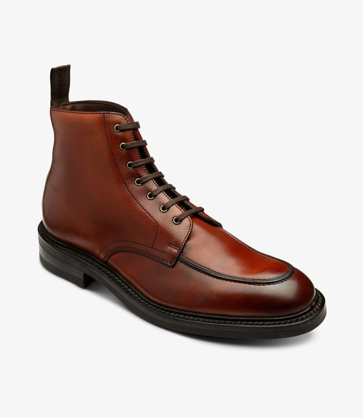 In this photo, the boot is presented at a slight angle, revealing the intricately crafted eyelet detailing and lacing. This perspective highlights the graceful curve of the ankle and the distinctive shape of the toe box. The boot's premium leather appears both soft and robust, promising style and longevity.