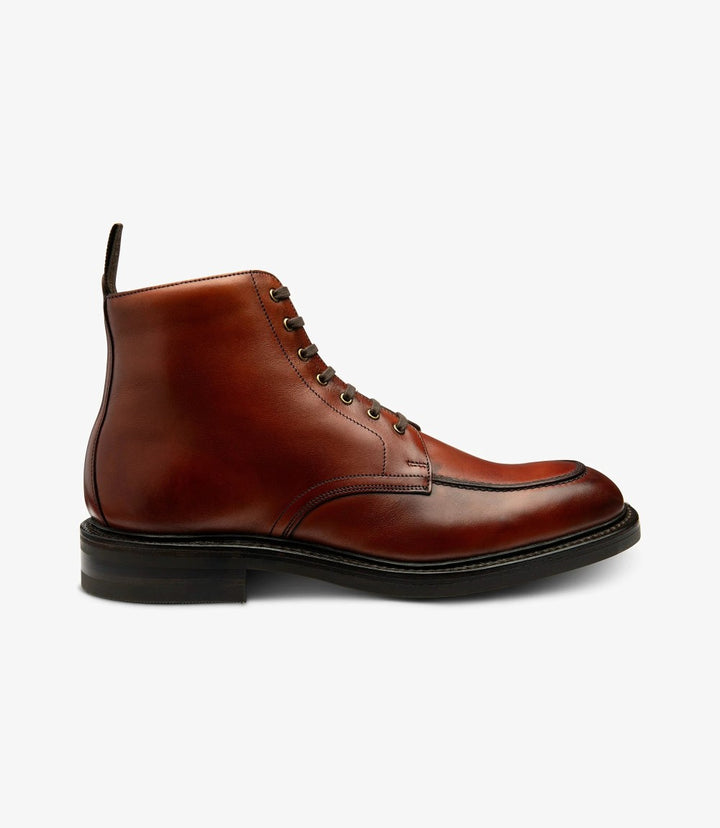 The image showcases the Loake Gisbourne Mahogany Derby Boot from the side, highlighting its elegant silhouette. The rich mahogany hand-painted calf leather gleams under the light, emphasizing the boot's refined finish. The Goodyear welted victory rubber sole is visible, offering a glimpse of its durability and traction.