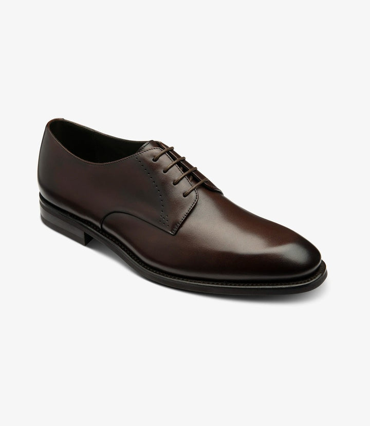 This angle provides a dynamic view of the shoe, displaying its elegant curvature and refined details. The intricate stitching along the seams enhances the shoe's aesthetic, while the slightly elevated heel offers a glimpse of the sturdy rubber sole. The light catches the leather, accentuating its luxurious finish.