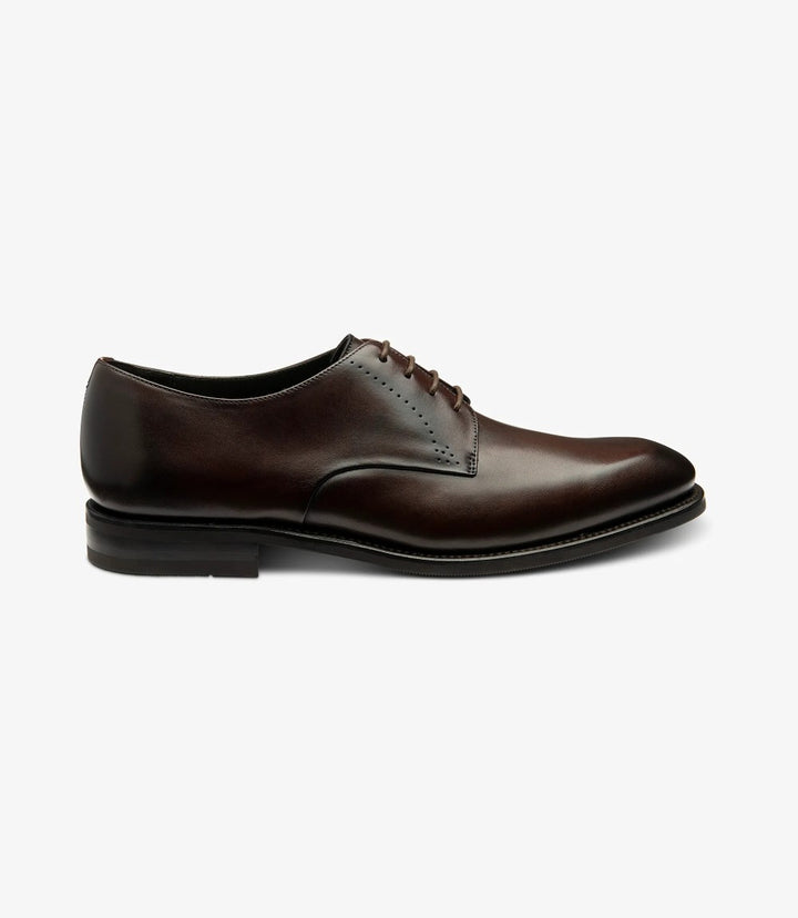 The image captures the side profile of the Loake Gosling Dark Brown Derby Shoe. The sleek silhouette showcases the rich, polished calf leather, highlighting its sophisticated dark brown hue. The Goodyear welted shadow rubber sole is visible, emphasizing durability and craftsmanship.