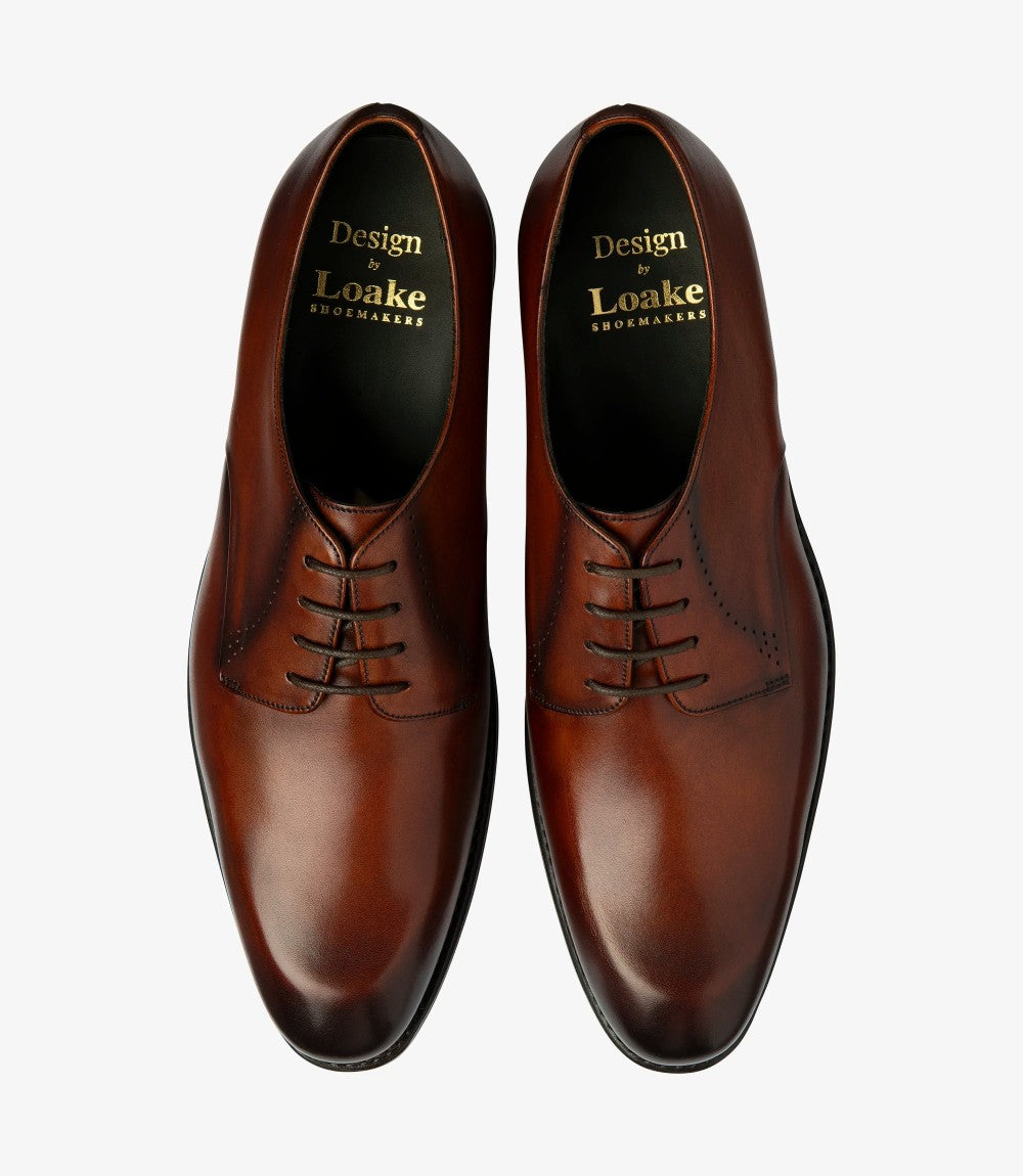 The top-down view showcases both shoes side by side, displaying their matching scotch leather finish and the intricacies of the brogue detailing. The neatly laced design gives a refined appearance, while the leather-lined interior hints at the comfort and quality that awaits the wearer. The symmetrical design and sleek profile suggest versatility for both formal and casual occasions.