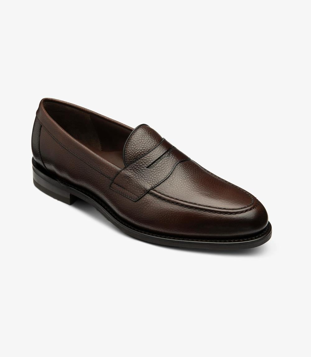 From this angle, the Imperial Grain Dark Brown Loafer reveals its stylish contours and expertly crafted shape. The smooth lines of the burnished grain calf leather flow seamlessly from the toe to the heel, while the classic apron design is complemented by subtle stitching details. The shadow rubber sole is visible, highlighting the shoe's robustness. This perspective showcases the meticulous craftsmanship, reflecting the loafer’s blend of practicality and elegance.