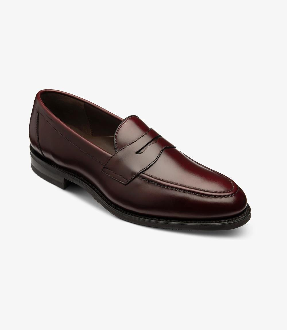 The first image showcases the Imperial Burgundy Loafer from a side angle, highlighting its sleek silhouette and elegant design. The polished burgundy leather glistens under the light, accentuating the shoe’s refined craftsmanship. The classic apron design features a subtle stitched detail that adds character, while the Goodyear welted sole provides a glimpse of the durability and quality craftsmanship synonymous with Loake.