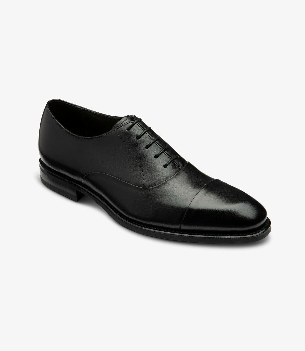 In this shot, the shoe is presented at a dynamic angle, showcasing both the toe-cap detail and the curve of the vamp. The smooth texture of the leather contrasts beautifully with the robust rubber sole, emphasizing the craftsmanship of the Loake Design Collection. This perspective also reveals the comfortable leather lining within the shoe.

