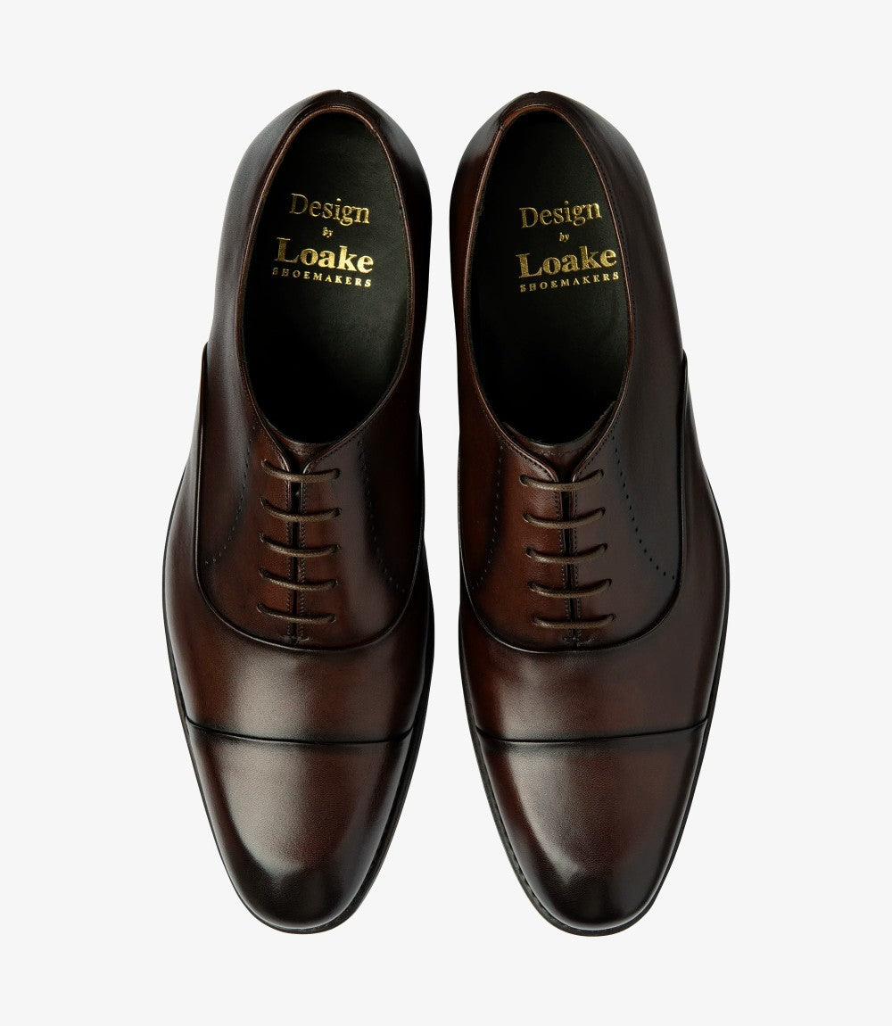 The top-down view features both shoes side by side, revealing the symmetrical design and the exquisite craftsmanship. The comfortable leather insoles and fully leather-lined interiors can be inferred, suggesting luxury and comfort. The rich dark brown color contrasts beautifully with the shadow rubber soles, making these oxfords a striking addition to any wardrobe.