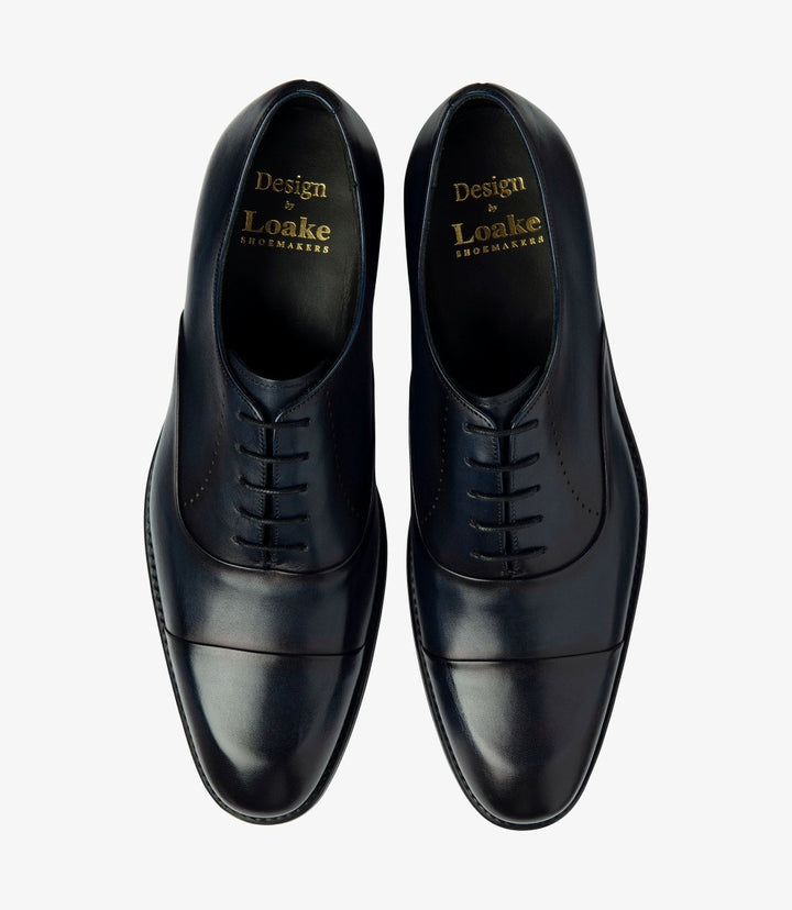 The overhead shot features both Loake Phoenix Oxfords side by side, offering a clear view of their matching elegant design. The uniform navy color and toe cap detailing are visible, along with the fully leather-lined interiors. This angle highlights the shoes' symmetry and sophistication, making them an ideal choice for any formal occasion.