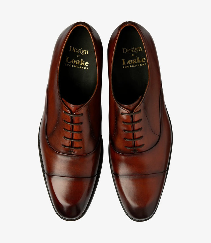 A bird’s-eye view of both Loake Phoenix Oxford shoes highlights their symmetrical design and quality construction. The rich scotch calf leather surface reflects light beautifully, while the elegant toe caps and clean lines present a harmonious look. This view captures the essence of sophistication and attention to detail that defines these men’s oxfords.