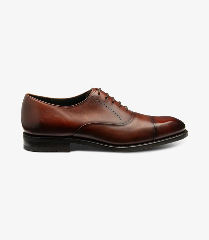 A sleek side profile of the Loake Phoenix Scotch Oxford Toe Cap shoe showcases its elegant silhouette. The hand-painted scotch calf leather glimmers under the light, highlighting the rich texture and quality of the material. The classic toe cap design adds a refined touch, making it a versatile choice for both formal and casual occasions.