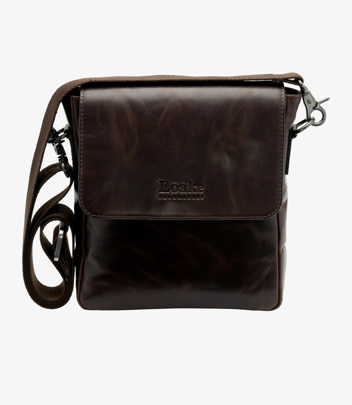 The front view showcases the Loake Stratford Dark Brown Crossbody Bag, highlighting its elegant fold-over flap design. The flap is adorned with a polished buckle and a discreet press-stud fastening, adding sophistication to the bag. The rich vintage dark brown waxy leather has a slightly distressed finish, giving it a rugged yet refined character. The signature Loake logo is subtly embossed, enhancing the bag's luxury appeal.