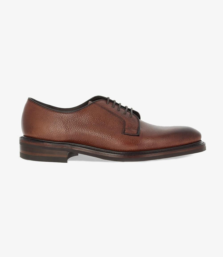 The Loake Troon Rosewood Derby shoe’s side profile highlights the rich grain burnished calf leather with a deep rosewood hue. The sleek derby design and fine stitching detail add an elegant touch, while the Goodyear welted stud rubber sole provides a robust yet polished look.