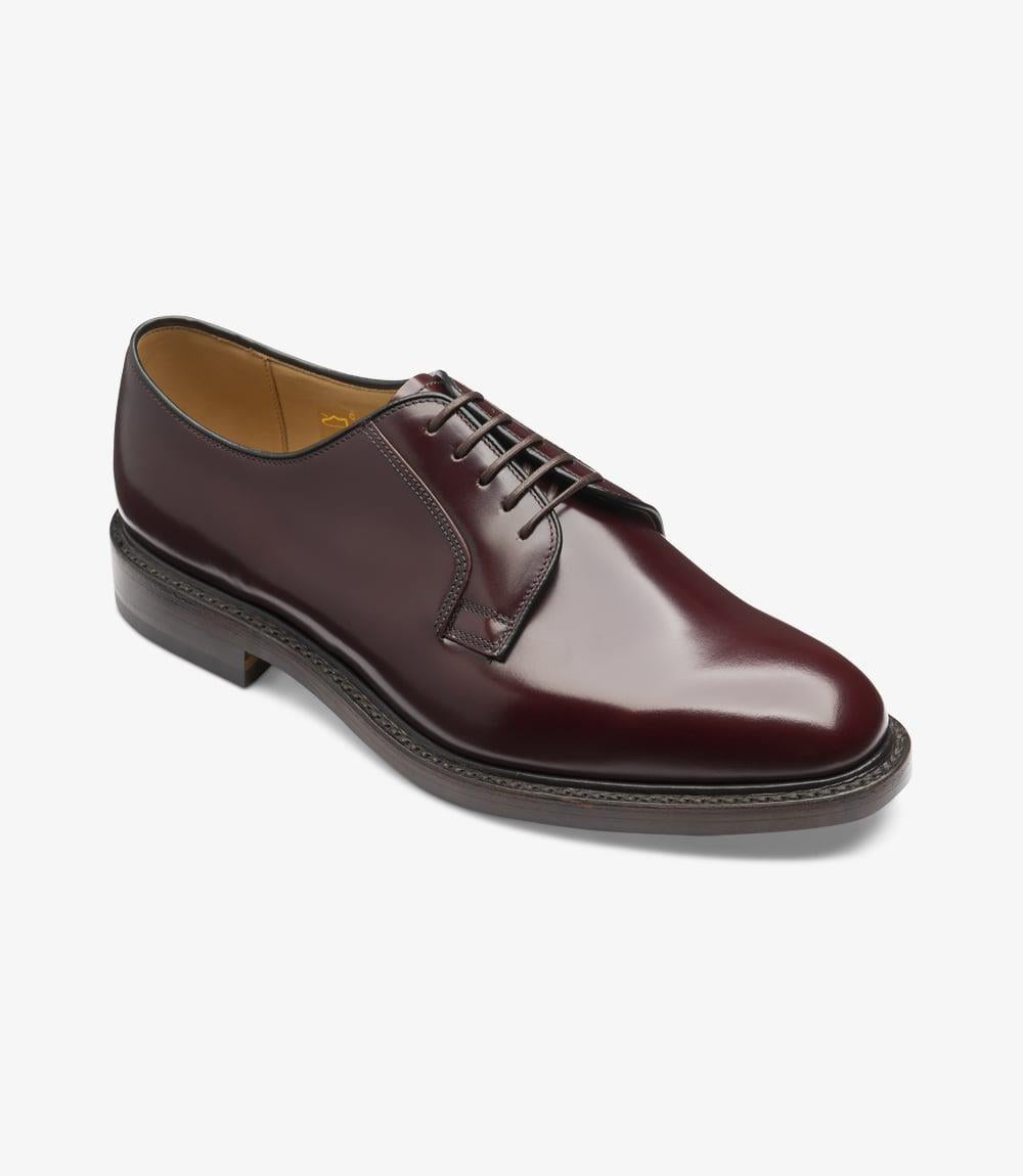 The Loake 771 is captured at a slight angle, highlighting the curved lines of the Derby style. The leather has a rich, polished burgundy hue, with the lacing area, eyelets, and finely stitched welt adding detail to the shoe’s sophisticated look. The angle also reveals the depth and shine of the leather.