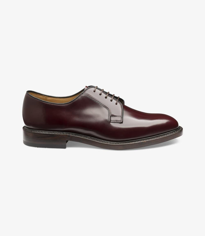 A close-up of the Loake 771 Burgundy Derby shoe from the side, showing the polished burgundy leather with a smooth finish, plain toe design, and subtle stitching along the Goodyear Welted double leather sole. The classic silhouette and slightly angled heel are visible, showcasing the shoe’s elegant structure.