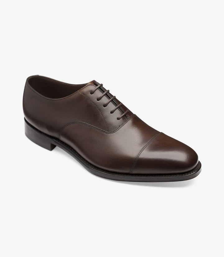 This photo presents the Aldwych Oxford from a dynamic angle, capturing the shoe's depth and details. The slight curvature of the shoe is accentuated, showcasing the contours that hug the foot. The glossy mahogany leather reflects light beautifully, while the toe-cap adds a touch of classic elegance. The image emphasizes the sturdy yet refined silhouette, making it clear that these shoes are designed for both style and comfort.