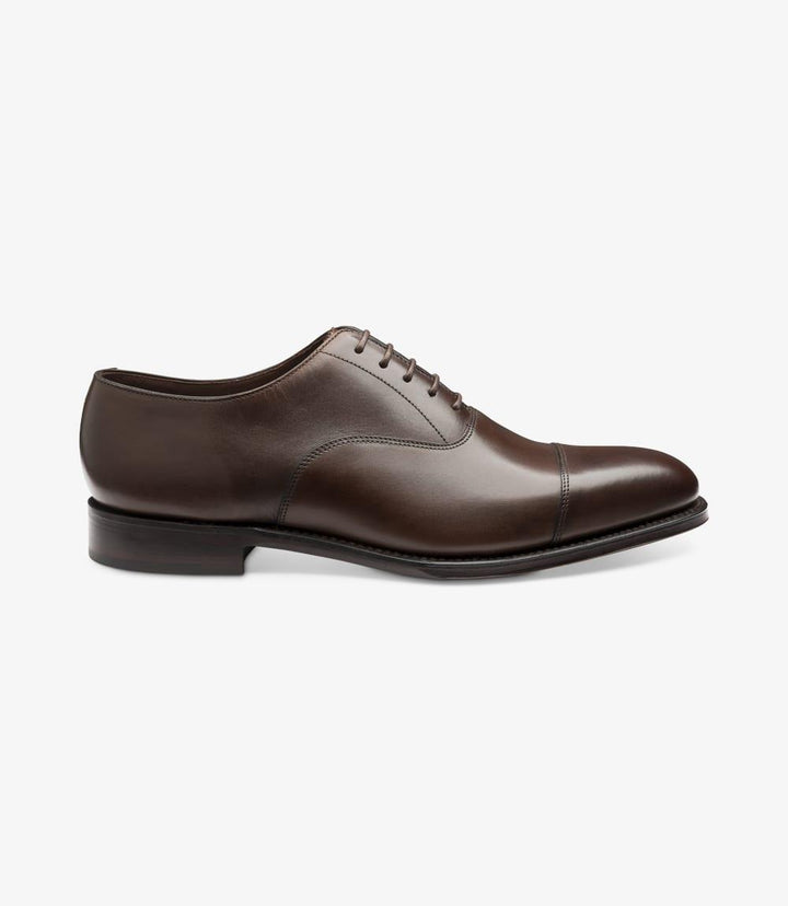 The image showcases the Aldwych Mahogany Oxford Toe-Cap shoe from the side. The smooth mahogany leather exhibits a rich, warm hue, highlighting the shoe's elegant profile. The toe-cap design adds sophistication, while the sleek lines lead to a polished finish. The Goodyear welted construction is subtly visible, indicating quality craftsmanship.