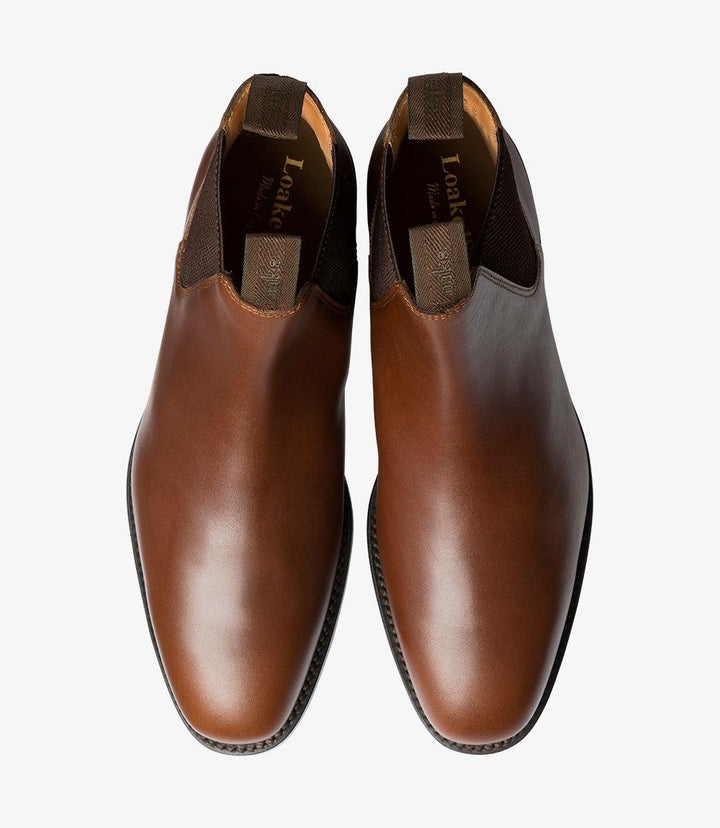 This overhead shot of the Loake Chatsworth Chelsea Boots provides a clear view of the symmetrical design and the elongated shape of the toes. The high-quality leather is smooth and polished, reflecting light in a way that showcases the craftsmanship. The elastic panels are neatly aligned, and the stitching around the edges is detailed, reinforcing the boot's durability.