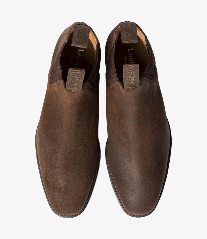  In this overhead view, both Chelsea boots are positioned side by side, allowing for a clear look at the smooth, waxed suede upper and the elegant shape of the boots. The elastic side panels are prominently displayed, showcasing the functional yet stylish aspect of the design. The contrasting tones of the waxed suede and the dark rubber soles create a striking visual appeal.