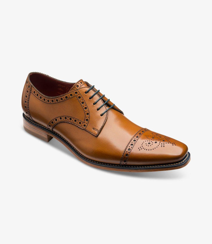 This angled shot captures the Loake Foley Semi Brogue from a dynamic perspective, emphasizing the curvature of the ‘Ridge’ last shape. The intricate punched decorations on the toe-cap catch the light, creating a striking contrast against the smooth leather. The shoe’s sleek profile is complemented by its sturdy leather sole, making it a perfect blend of style and functionality.