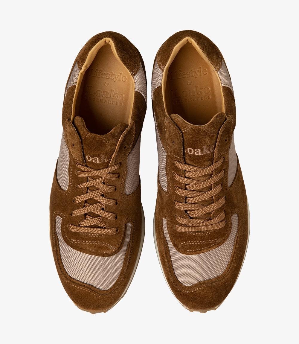 The image displays both Foster Tan Sneakers from above, perfectly aligned to reveal their symmetrical design. The sneakers' laces are neatly tied, and the inner leather lining is subtly visible, suggesting comfort and quality. This angle showcases the overall aesthetic, making them look appealing and stylish, suitable for any casual outing.