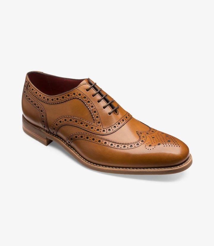 From an angled perspective, the Kerridge reveals its elegant Oxford brogue pattern with a sophisticated tan leather body. The shoe’s smooth vamp and intricate broguing across the toe cap and quarters highlight its refined craftsmanship. The Claridge last shape gives the shoe a balanced, slightly elongated appearance, while the rubber sole and low heel add a robust yet sleek touch, making it versatile for both formal and semi-casual occasions.