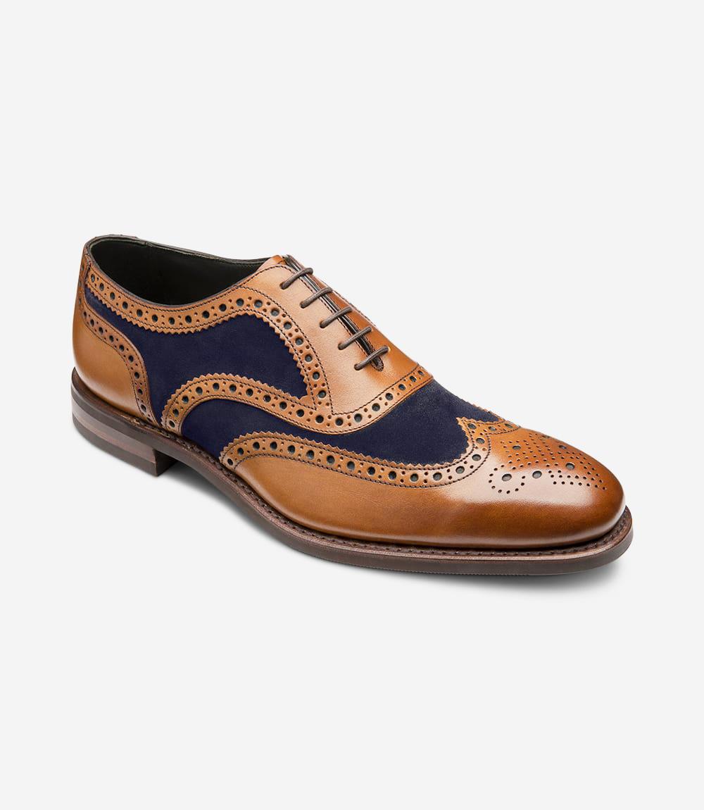 At an angle, the Kerridge shoe highlights its classic Oxford brogue design, with a beautifully hand-painted tan leather body and a sleek navy accent along the upper. The finely perforated brogue pattern wraps around the toe cap and down the sides, while the Claridge last shape offers a balanced, elongated profile. The Goodyear welted sole adds a robust yet refined touch, combining elegance with durability.