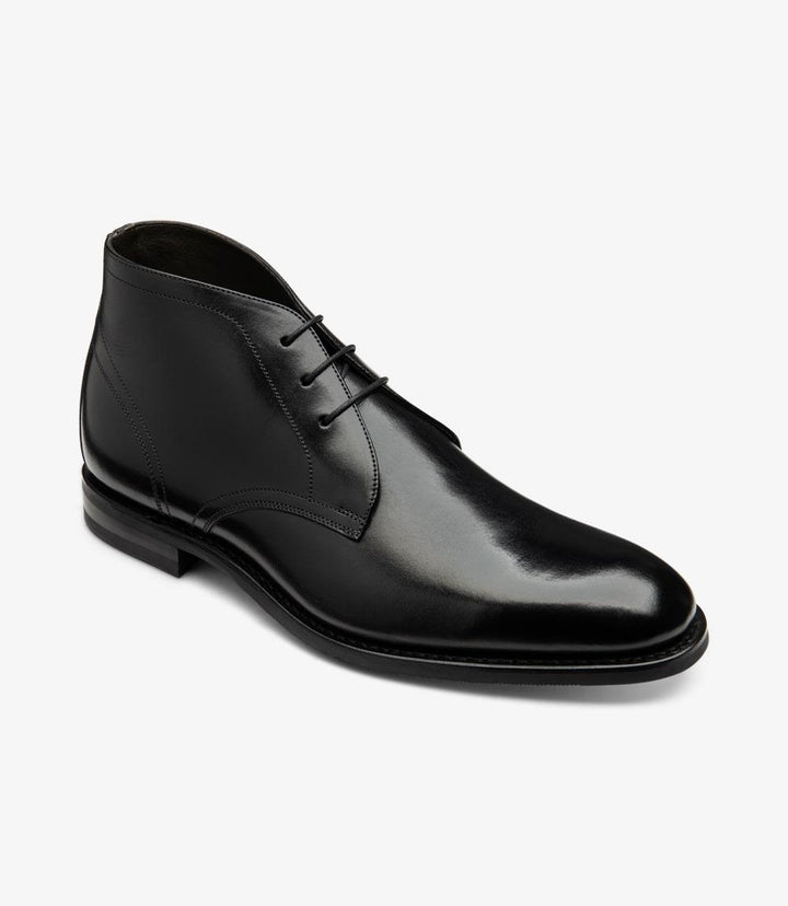 In this angled view, the Loake Myers Black Chukka Boot reveals its sophisticated contours and attention to detail. The slightly rounded toe adds a contemporary touch, while the 3-eyelet lacing system is positioned for easy adjustability. The transition from the calf leather upper to the Goodyear welted rubber sole showcases the craftsmanship involved in creating a durable and stylish boot. This perspective emphasizes the elegant lines and the subtle sheen of the leather.