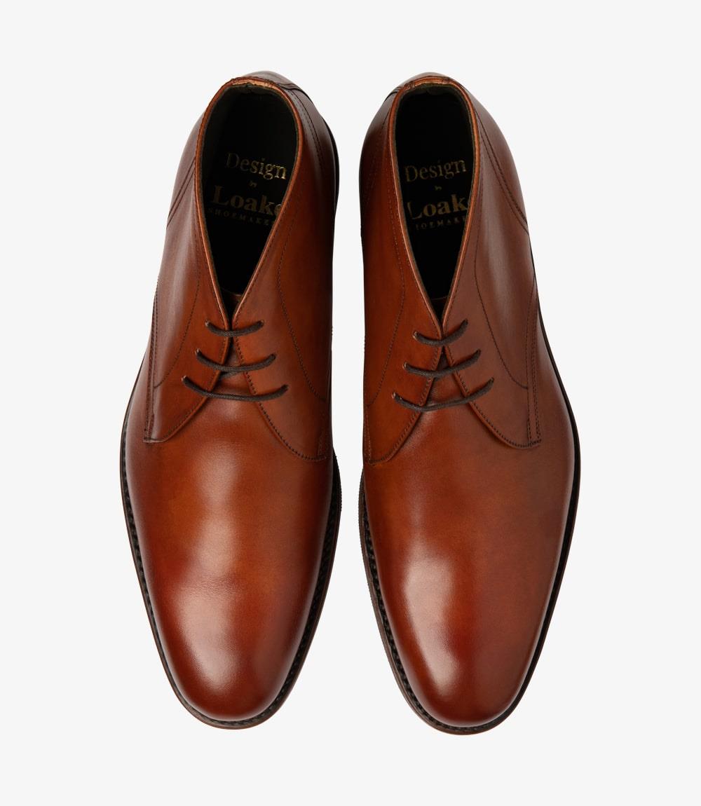 From above, the pair of Loake Myers Tan Chukka Boots showcases their symmetry and craftsmanship. The 3-eyelet lacing allows for a personalized fit, while the smooth, warm tan leather covers the upper with a luxurious sheen. The slight curve of the toe and the subtle brogue detailing are evident, highlighting the boots' classic design. The fully leather-lined interiors and insoles are visible, hinting at the quality and comfort that these men's boots provide.