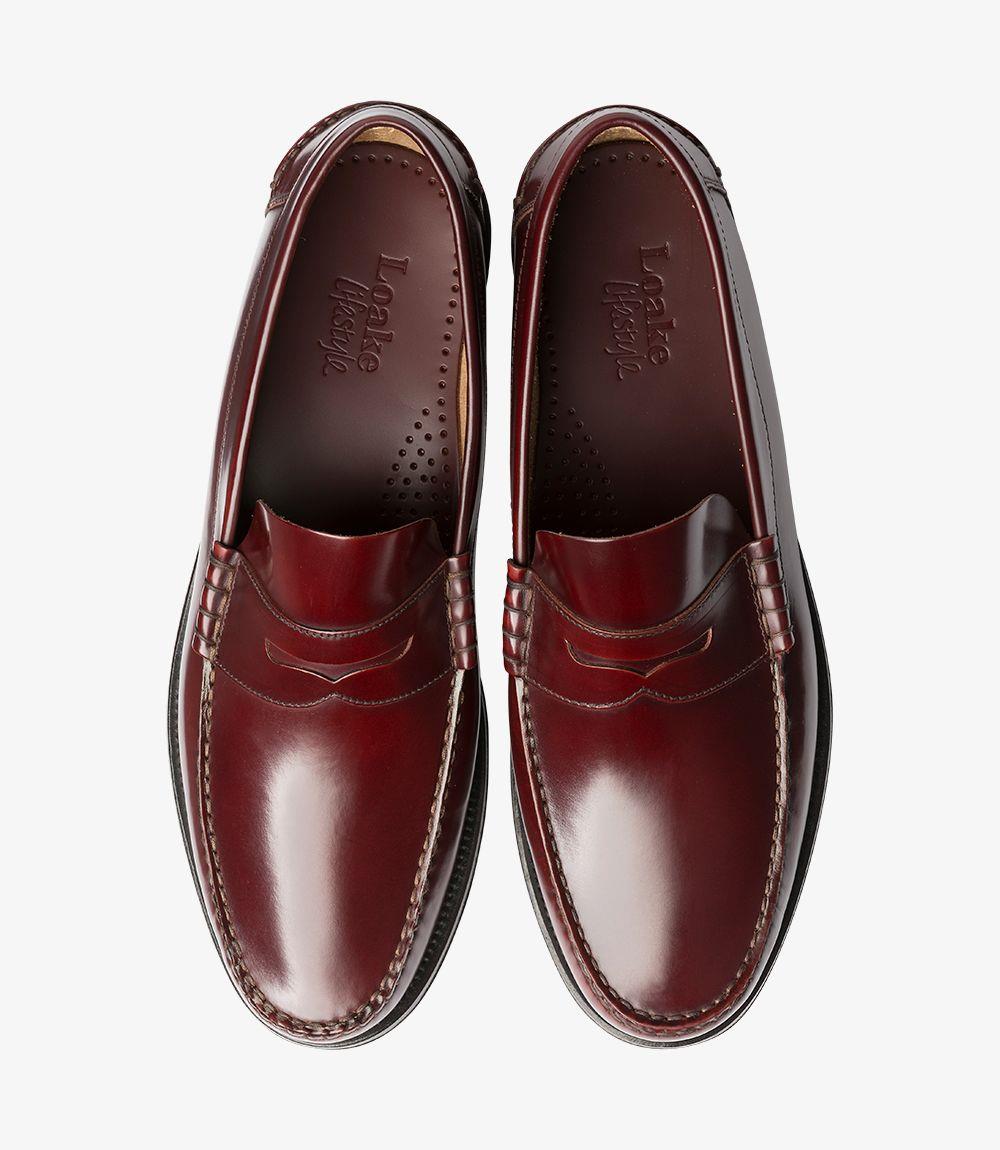 The top view of the Loake Princeton Burgundy Loafers highlights the symmetrical design and luxurious finish of both shoes. The polished leather surface reflects light, enhancing the deep burgundy color. The beef-roll detailing runs along the sides, framing the rounded toe and contributing to the loafer's classic appeal. This perspective emphasizes the comfortable fit and high-quality craftsmanship, making these loafers a stylish addition to any wardrobe.