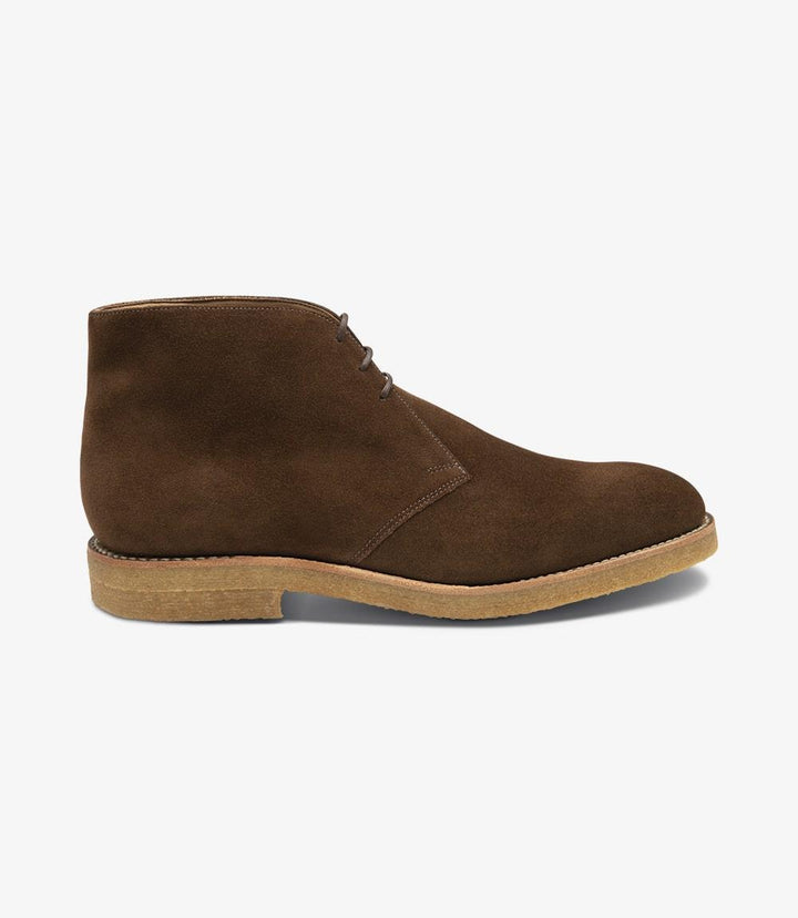 The side profile of the Loake Rivington Brown Chukka Boot showcases its sleek silhouette and elegant lines. The rich brown suede leather has a soft, luxurious texture that catches the light beautifully, highlighting the boot's refined craftsmanship. The crepe sole adds a touch of modernity while providing a sturdy foundation, making this chukka boot both stylish and practical.