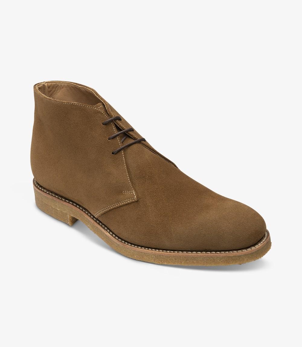 From this angle, the distinctive features of the Rivington boot are clearly visible. The bold toe shape and the gently curving upper create a refined silhouette that is both contemporary and timeless. The lacing system is elegantly integrated into the design, allowing for a customizable fit. The smooth transition from the suede upper to the crepe sole emphasizes the quality craftsmanship, making this chukka boot a versatile addition to any wardrobe.