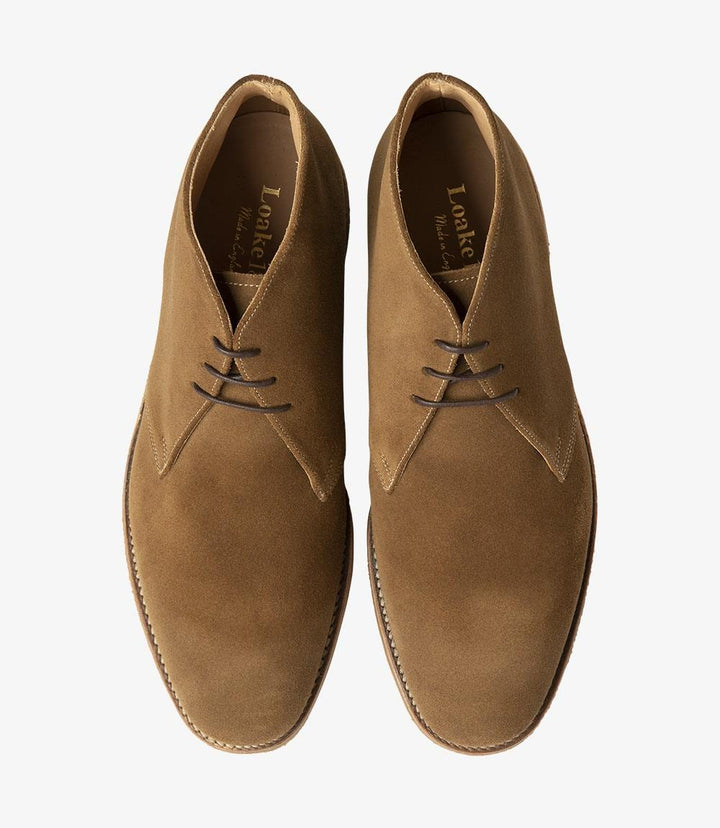 The top view of the Loake Rivington Tan Chukka Boot showcases its classic lace-up design, with neatly arranged laces and eyelets that enhance its sophisticated look. The supple suede surface offers a rich and warm tone, inviting a closer inspection. The boot's rounded toe is slightly prominent from this angle, underscoring its standard length and suitability for wider feet. The crepe sole is subtly visible, highlighting the boot’s durable construction and comfort features, perfect for everyday wear.