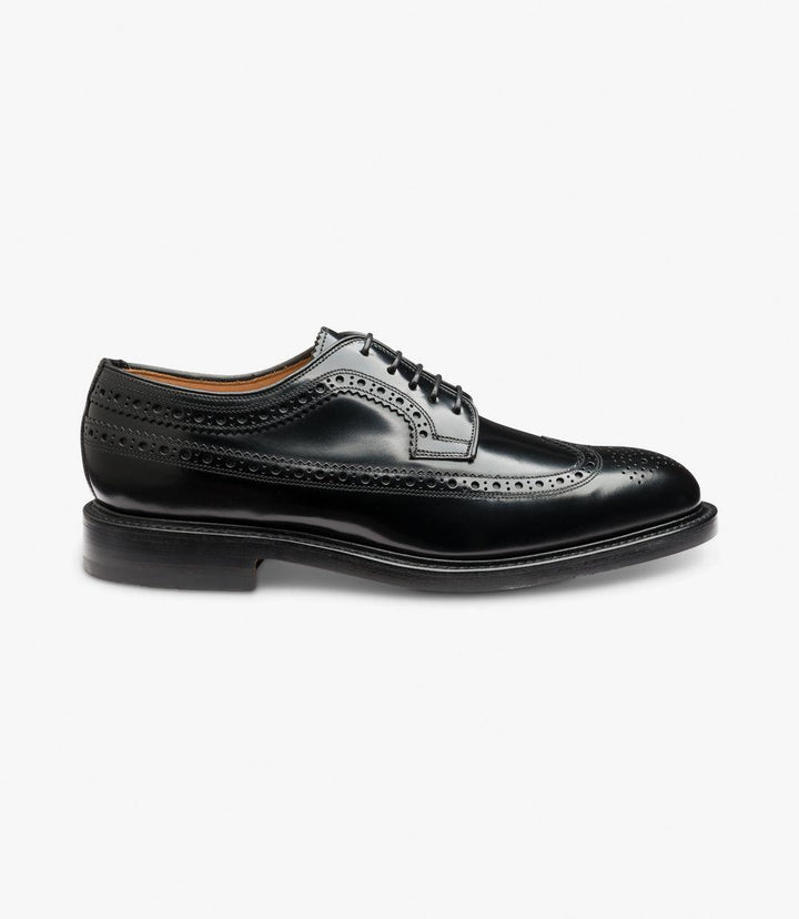 The side view of the Loake Royal Black Derby Brogue showcases its elegant long-wing design, with intricate brogue perforations running along the seams and a polished black leather finish. The double leather sole is visible from the side, adding a touch of refined durability and structure.