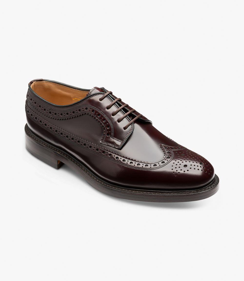 Viewed from an angled perspective, this shoe’s refined silhouette stands out, with the slightly rounded toe, decorative brogue perforations, and smooth polished finish catching the light. The combination of deep burgundy leather and hand-crafted detailing offers a luxurious and distinguished look.