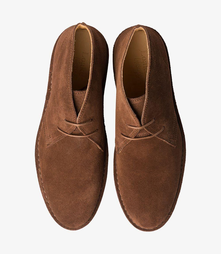 The top-down view of the Sahara Tan Chukka Boot reveals the layout of the three-eyelet lacing system, demonstrating the boot's easy adjustability for a secure fit. The premium suede leather appears soft and inviting, with the natural grain and texture adding depth to the design. The rounded toe shape is highlighted, providing a classic look that is true to size for most wearers. The boot's clean lines and polished finish emphasize its quality, making it suitable for both casual and smart-casual outfits.